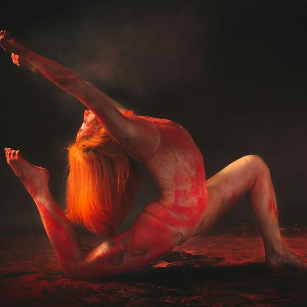 Person in a dynamic yoga flow pose against a dark background.