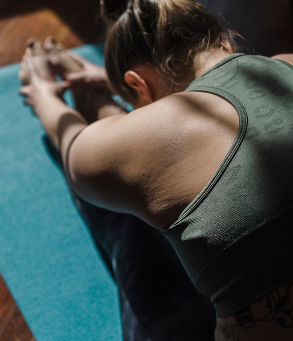 Woman performing a serene yoga pose in a softly lit room.
